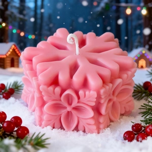 Pink snowflake pillar candle with floral relief on festive winter background