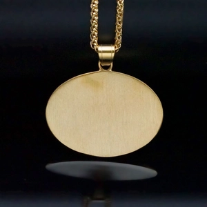 Macro shot of oval gold-plated pendant with brushed metal texture on rope chain