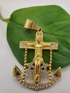 Macro detail of a gold-plated anchor cross pendant with Jesus relief and zircon inlays