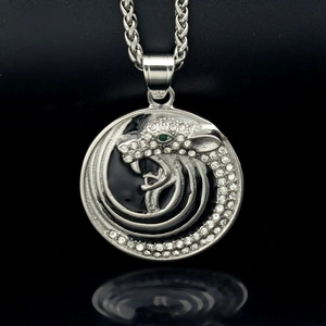 Pendentif tête de loup argenté avec strass blancs et verts sur fond noir élégant