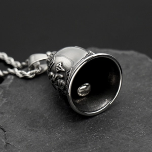 Macro shot of stainless steel biker bell pendant with skull and cross on rock base