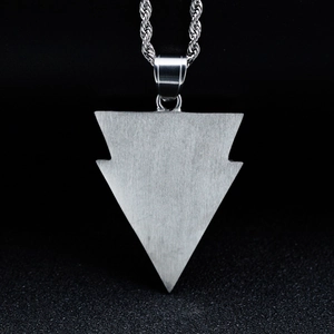 Close-up of brushed silver arrow pendant with rope chain on dark background
