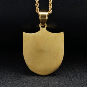 Macro shot of gold shield pendant featuring a brushed metal finish and rope chain