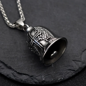 Vintage stainless steel guardian bell necklace with cross wings on dark rock background