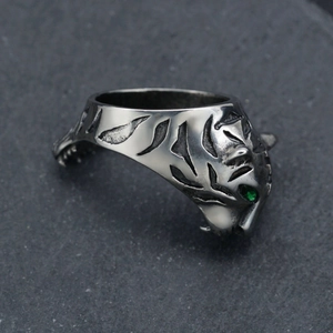 Vintage stainless steel tiger head ring with green gemstone eyes on stone background