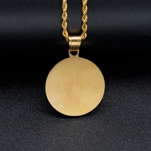 Macro shot of gold brushed metal round pendant with an elegant rope chain on black texture