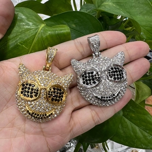 Primer plano de colgantes hip-hop de plata y oro con piedras engastadas en la mano