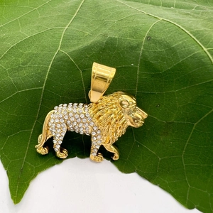 Vue détaillée du pendentif lion plaqué or avec cristaux blancs sur une feuille verte