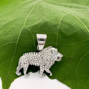 Détail macro du pendentif lion argenté hip-hop avec cristaux sur une feuille verte