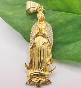 Detail of gold-plated Virgin Mary pendant with inlaid rhinestones on a green leaf
