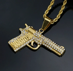 Macro detail of gold plated pistol pendant necklace with sparkling white crystals