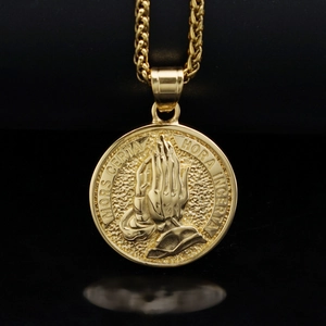Detailed view of gold praying hands medallion with Latin text engraving and woven chain