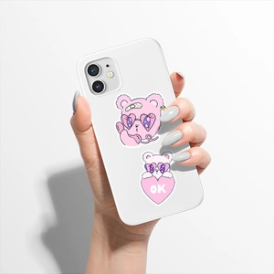 Close-up of waterproof cartoon bear stickers with pink heart and OK sign on phone case