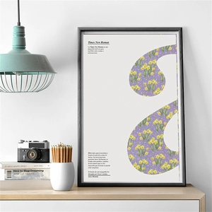 Detail showing a minimalist modern framed poster with yellow floral art on a wooden desk