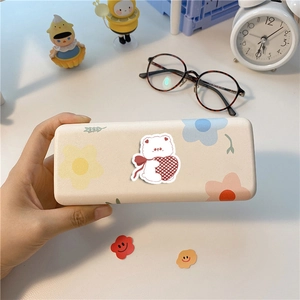 Étui de rangement avec ourson mignon et fleurs pastel tenu à la main sur un bureau