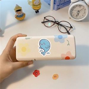 Creamy white glasses case with cute blue whale and floral patterns in a cozy desk setting