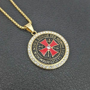 Macro shot of gold-plated Templar shield pendant with red cross and cubic zirconia inlay