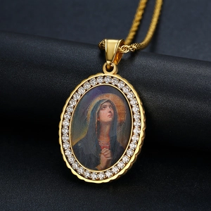 Dettaglio del ciondolo ovale della Vergine Maria dorato con zirconi su display nero