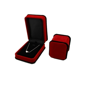 Red velvet jewelry box set with black trim for necklaces and rings on white background