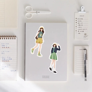 Close-up of waterproof summer girl character stickers on a journal with scissors and pen