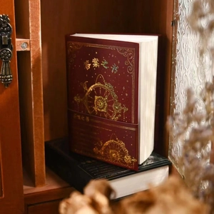 Detailed view of the dark red hardcover Book of Answers with gold foil clockwork design