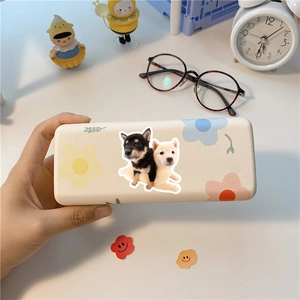 Handheld view of a beige storage box featuring cute Shiba Inu puppies and floral patterns