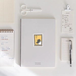 Cute black cat sticker on a minimalist stationery background with notebook and pen