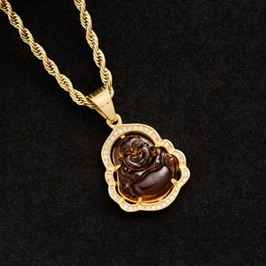 Macro dettaglio del ciondolo Buddha placcato oro con calcedonio marrone e bordi di cristallo