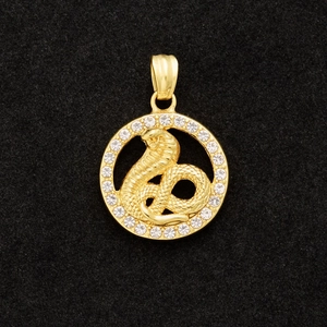 Macro shot of gold plated zodiac pendant featuring a detailed cobra with sparkling crystal border