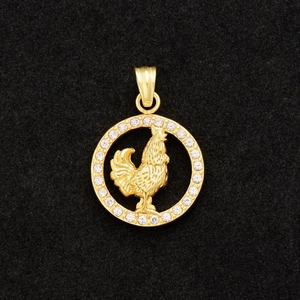 Macro shot of gold-plated rooster zodiac pendant with sparkling crystal inlay on black velvet