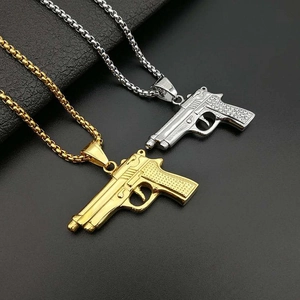 Macro shot of gold and silver M1911 pistol pendants with box chain on black leather