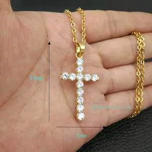 Detalle de colgante de cruz de 44mm en acero inoxidable dorado con gemas de circonita AAA