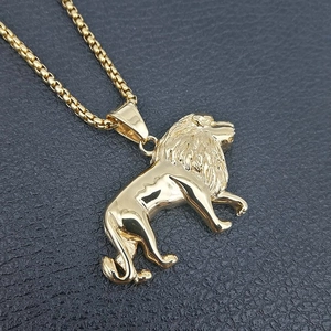 Polished gold lion head pendant necklace with box chain on a black textured background