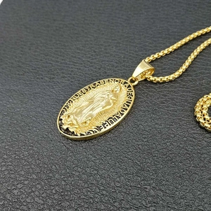 Primer plano del colgante Virgen de Guadalupe bañado en oro sobre fondo negro