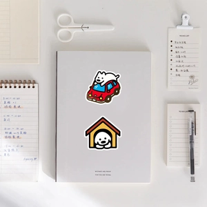 Detail of cute white dog stickers on a notebook with stationery and a mini red car design