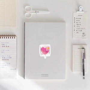 Close-up of pink heart lollipop sticker on desk with stationery and planner background