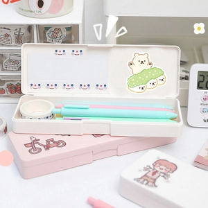 Close-up of cute cartoon bear stationery boxes in pink and cream with desk accessories