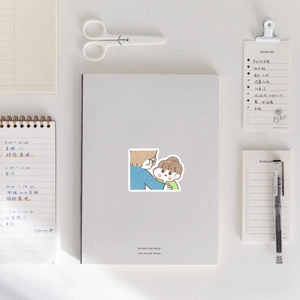 Close-up of cute cartoon couple sticker on notebook with stationery items