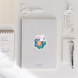 Close-up of pink bunny and flower stickers on a notebook with stationery background