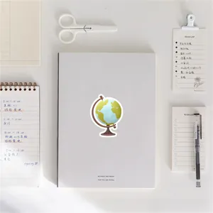 Cute globe sticker applied on a white notebook with office stationery on the desk