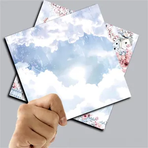 Detailed view of hand-held vintage scrapbook paper with blue sky and floral illustrations