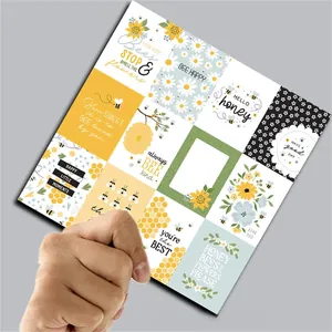 Detail of hand holding vintage bee themed scrapbooking papers with floral illustrations