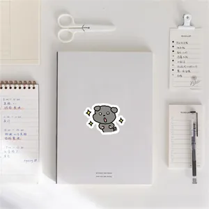 Detail of cute puppy cartoon sticker on a minimalist white notebook with stationery