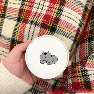 Close-up of white round makeup compact with minimalist gray cartoon cat illustration