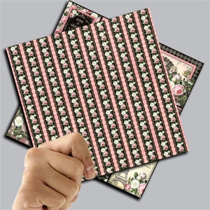 Close-up of hand holding vintage floral scrapbook paper with rose and stripe patterns