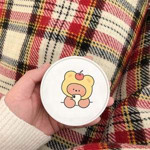 Close-up of a cute cartoon bear sticker featuring a cherry hat on a white round surface