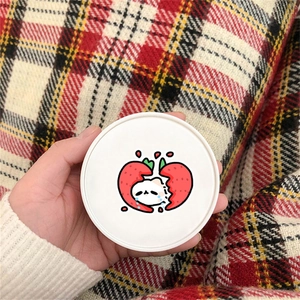 Close-up of a round container with cute strawberry cat sticker held in hand
