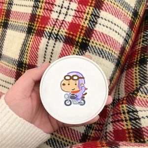 Cute cartoon dog sticker on round lid held by hand against red checkered background