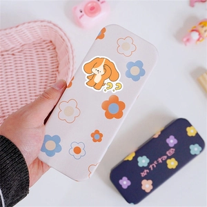 Close-up of a floral pattern eyeglass case with a cute dog sticker being held by hand
