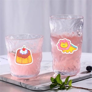 Hammered texture glass cups set with cute cartoon stickers on a white marble tray